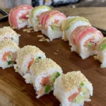 A wooden cutting board topped with sushi rolls.