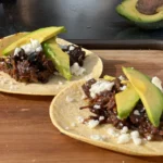 Two plates of food on a table with avocado.