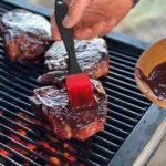 A person is cooking some meat on the grill.