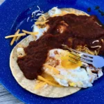 A blue plate topped with an egg and some meat.