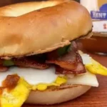 A bacon sandwich with an egg on top of it.