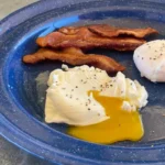 A blue plate with bacon, eggs and cheese.