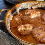 A pan of food with meat and sauce in it.