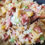 A close up of rice with ham and pineapple