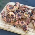 A wooden cutting board with some shrimp on it