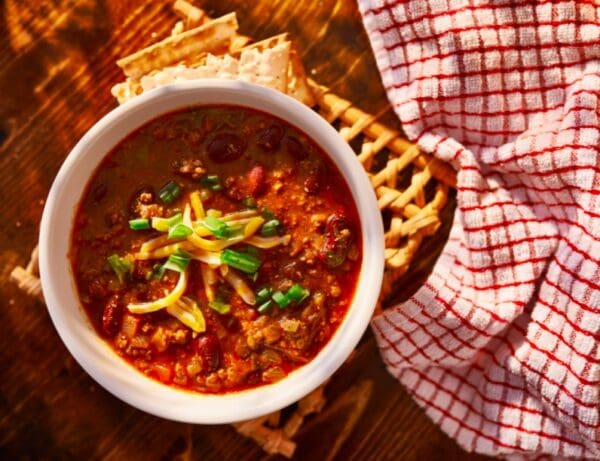 Bowl of chili with cheese and green onions.