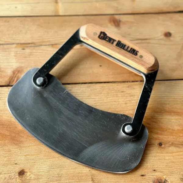 Bent Rollins brand cheese knife on wood.