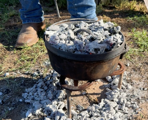 Cast iron pot on coals for cooking.