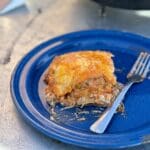 Lasagna on a blue plate with a fork.