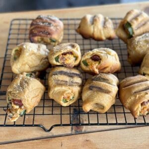 Grilled cheesy rolls on a wire rack.