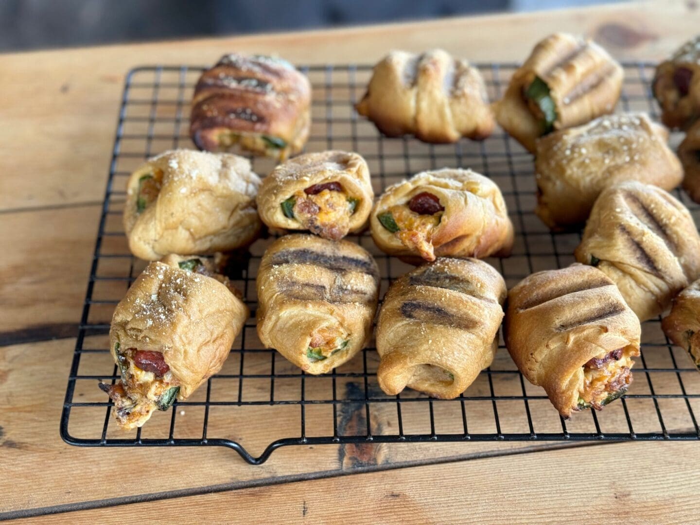 Grilled cheesy rolls on a wire rack.