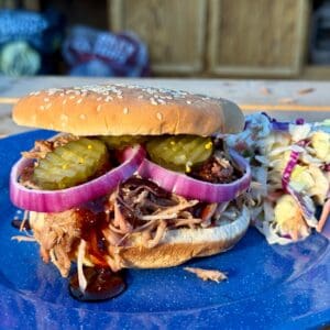 Kent Rollins Pulled Pork Sandwich on a blue plate with cole slaw