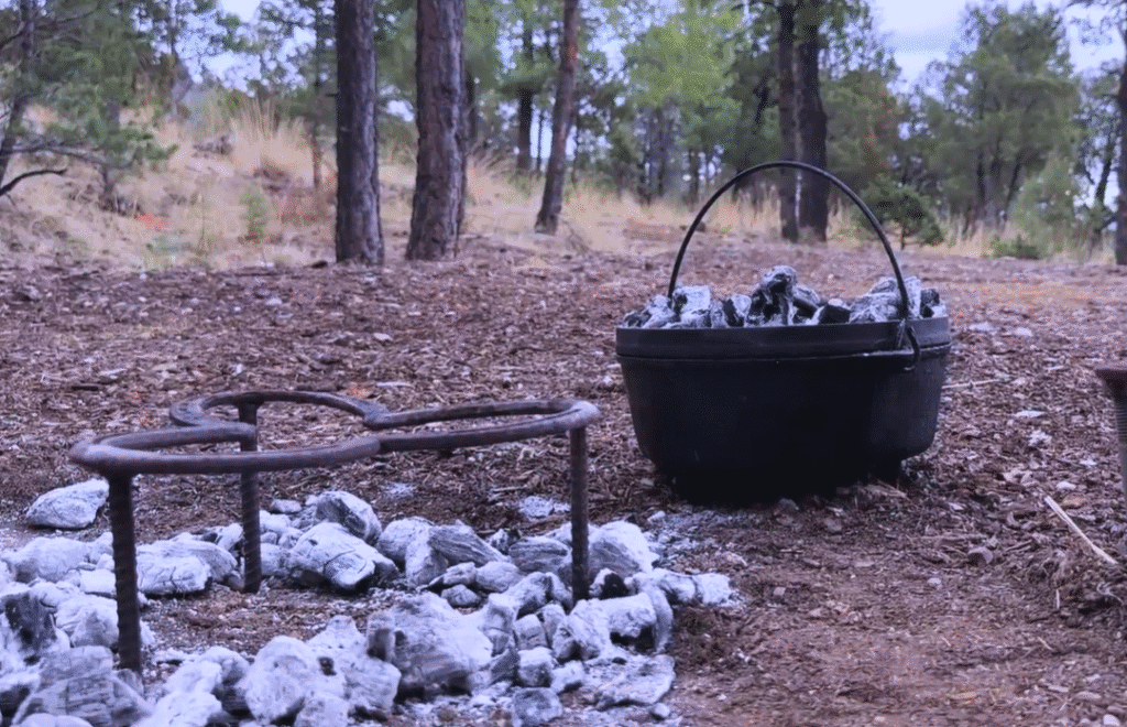 A trivet with hot coals surrounding it in a circle. This allows the heat to flow under the trivet to the cast iron Dutch oven.